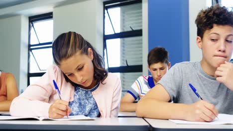 niño de escuela haciendo trampa durante el examen en el aula