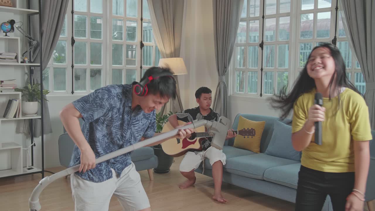 Young Asian Father And His Children Have Fun Singing Together At Living Room