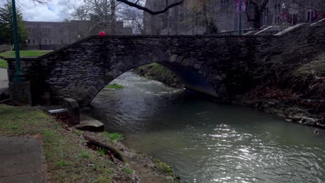 puente de piedra y arroyo corriendo en el campus de la universidad de indiana en bloomington, indiana con video estable