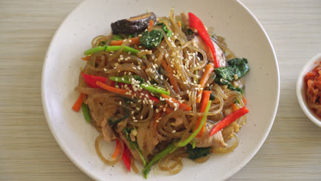 japchae o fideos vermicelli coreanos salteados con verduras y cerdo cubiertos con sésamo blanco - estilo de comida tradicional coreana