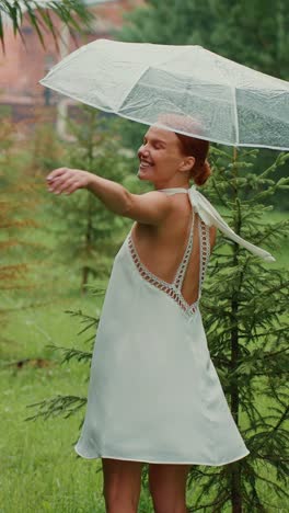 woman in a white dress enjoying a rainy day in a forest with an umbrella