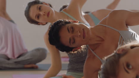 Yoga-Kurs:-Gesunde-Hispanische-Frau-übt-Sitzende-Seitenbeuge-Pose-Mit-Einer-Gruppe-Schöner-Frauen,-Die-Auf-Einer-Trainingsmatte-Sitzen-Und-Bei-Sonnenaufgang-Ein-Training-Für-Einen-Gesunden-Lebensstil-Im-Fitnessstudio-Genießen