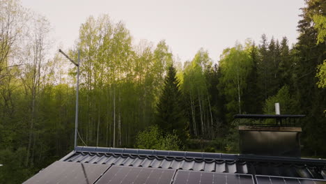 Aerial view backwards over a solar powered house, spring sunset in the forest