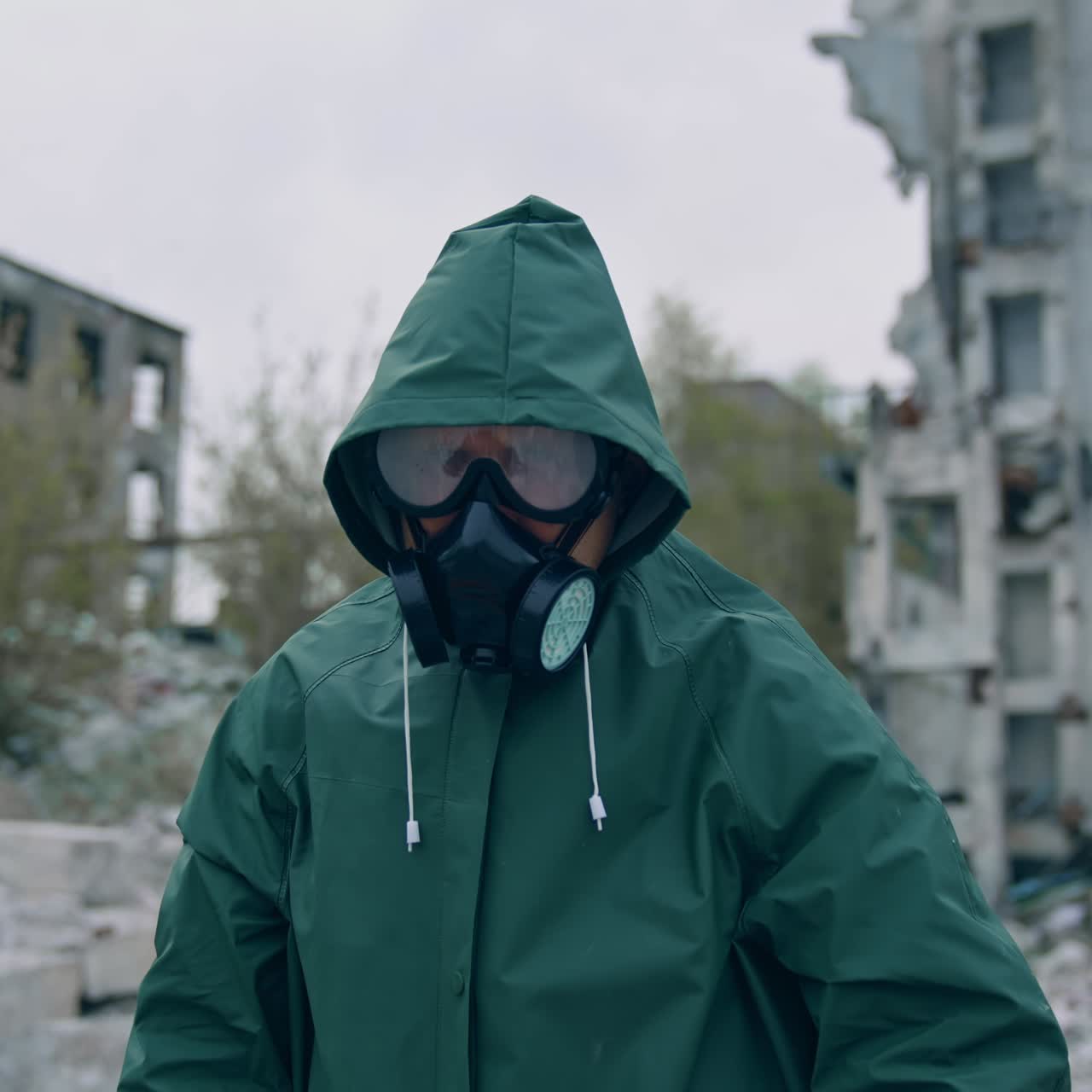 Im shocked. Ecologist in safety suit touching to his head on ruined building background. Person in gas mask and protective clothes stands in dangerous place after chemical attack