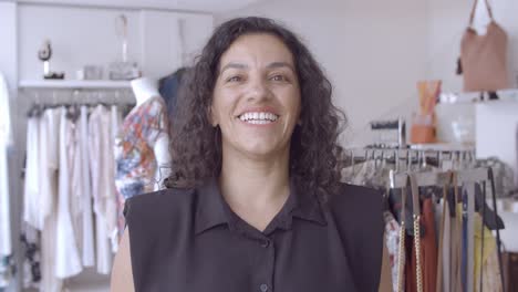 amable mujer de pelo negro latino de pie en la tienda de ropa