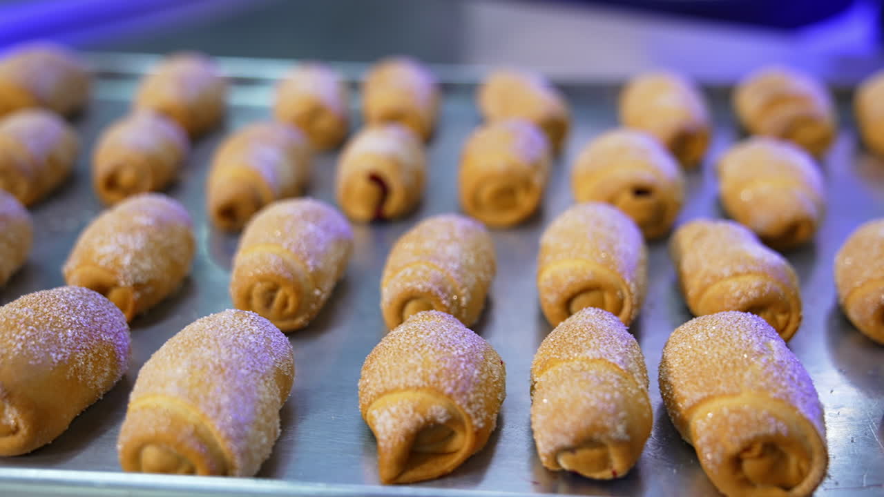 Tasty savory sweet desserts at the metal baking sheet. Freshly-baked croissants covered with sugar close up.