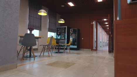 mesas con sillas cerca de máquinas expendedoras y cafeteras en la cafetería