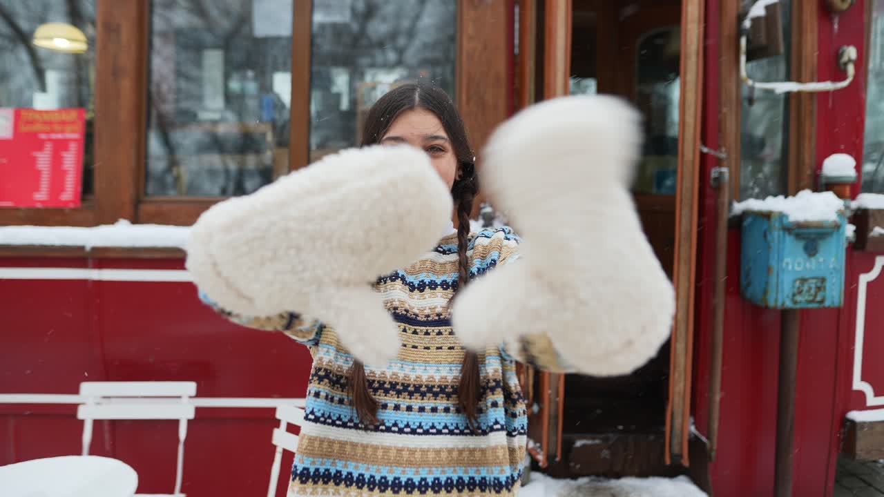 niña con guantes disfrutando de un día nevado en un café