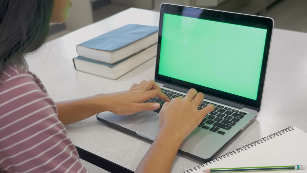 joven asiática trabajando en un nuevo proyecto en una computadora portátil con pantalla verde en blanco en la oficina, mujer escribiendo en el teclado mientras usa internet para la actividad en línea