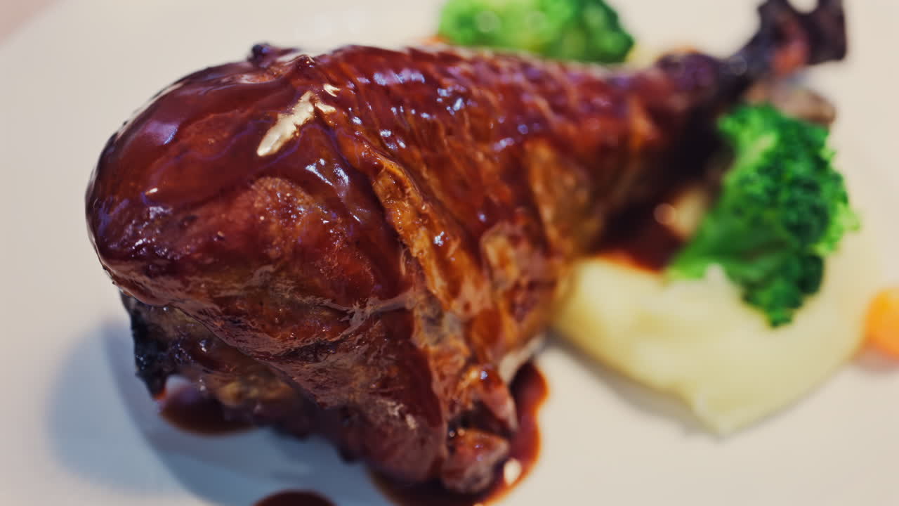Close up of chocolate pouring on a slice of cheesecake on a white plate