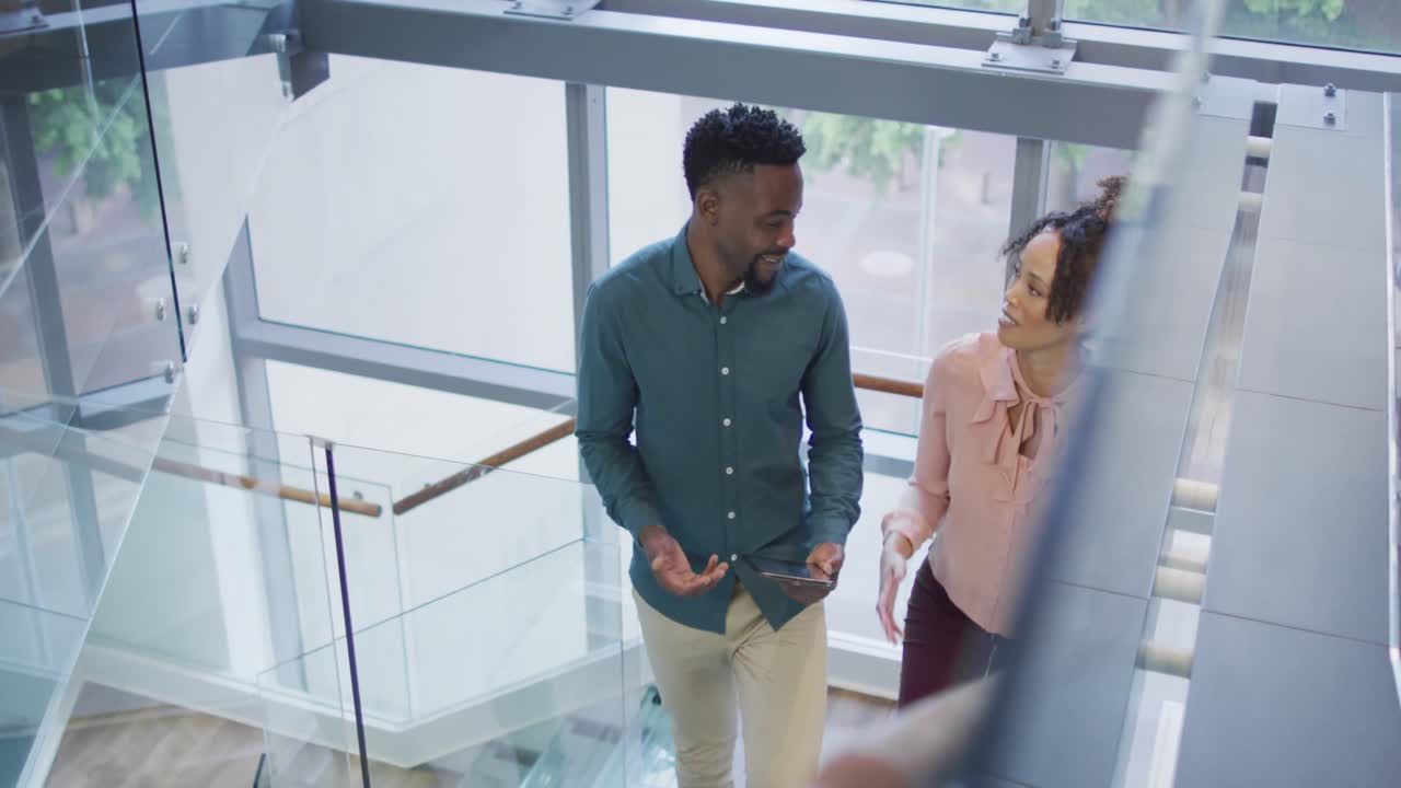 Diversos profesionales de negocios conversando con una tablet y caminando en una oficina creativa