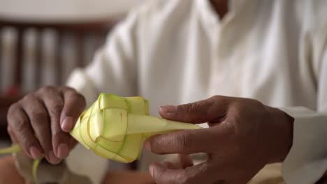 el proceso de hacer ketupat o kupat, una especialidad marítima del sudeste asiático hecha de arroz envuelto en un envoltorio hecho de hojas de coco tiernas tejidas o, a veces, otras hojas de palma