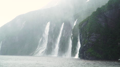 dramatic scenery with multiple waterfalls cascading into milford sound, rainy