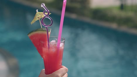 chica sostiene una bebida cerca de la piscina del hotel en las vacaciones de verano