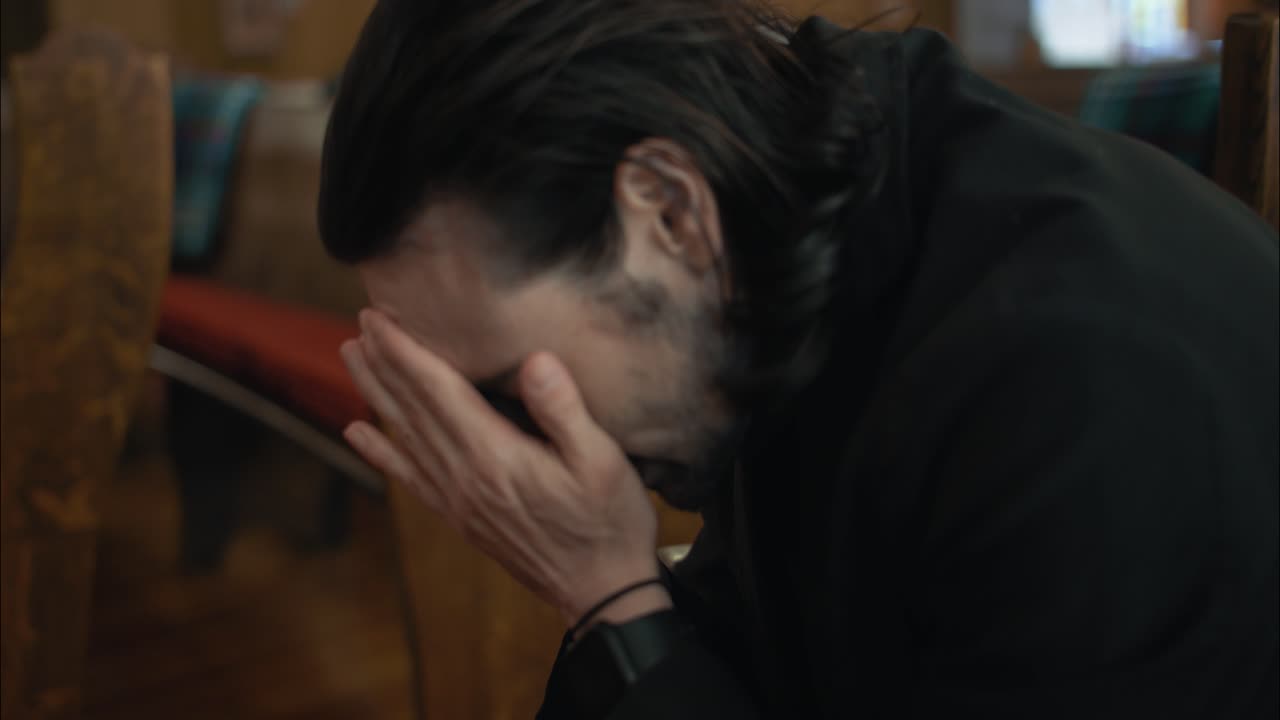 감정적, 스트레스를 받은 남자가 교회에서 그의 손에 얼굴을 넣습니다. 영화 속도 느린 동작으로.