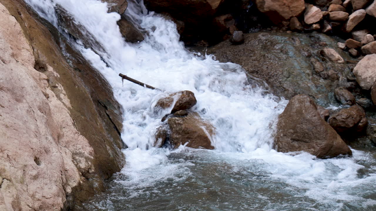 estrecho arroyo de agua de manantial en cascada a través de los senderos rocosos en las montañas