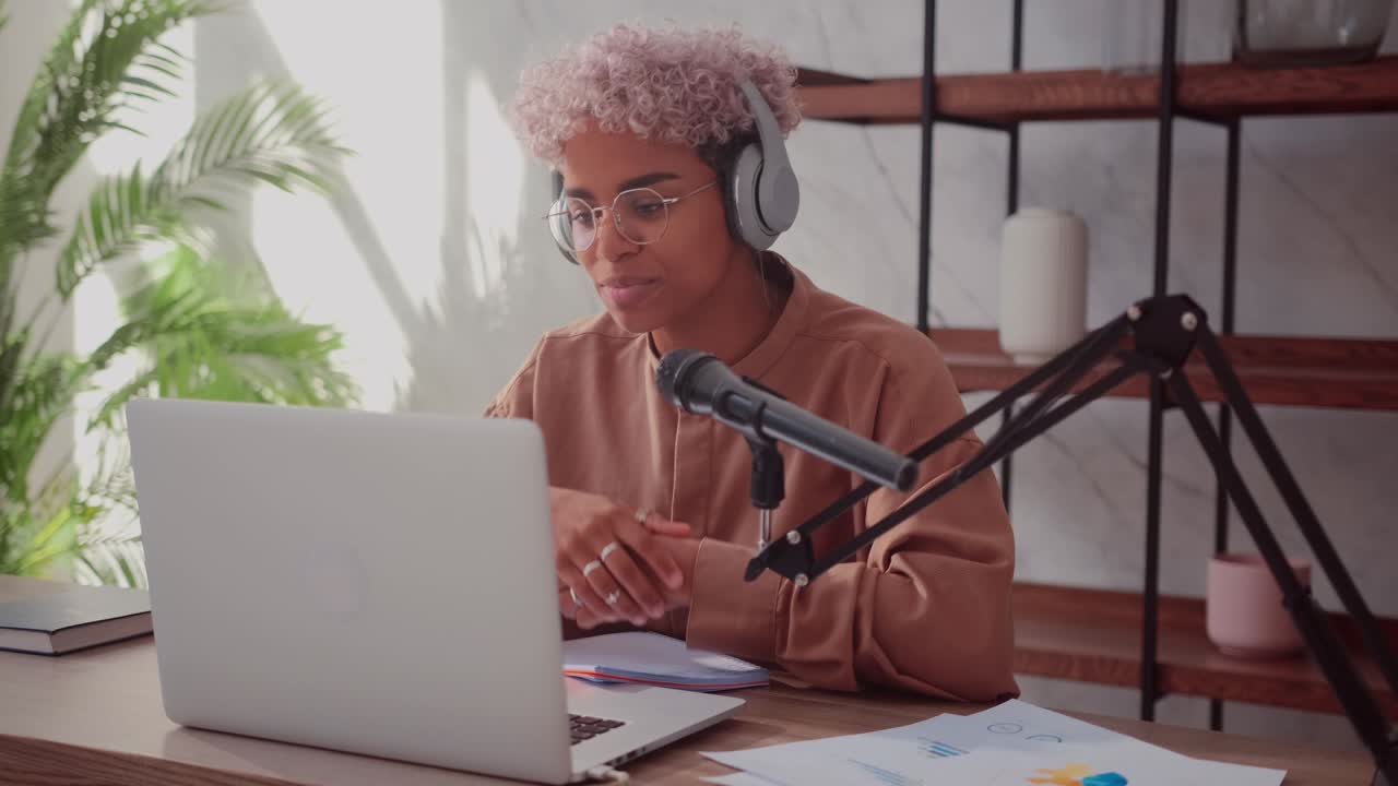 Black woman with blond curly hair puts on headphones and starts her radio show