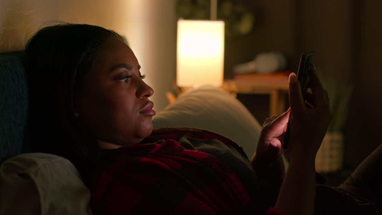 mujer usando teléfono móvil en la cama por la noche