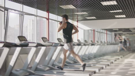 running man drinking water on treadmill machine in gym club.