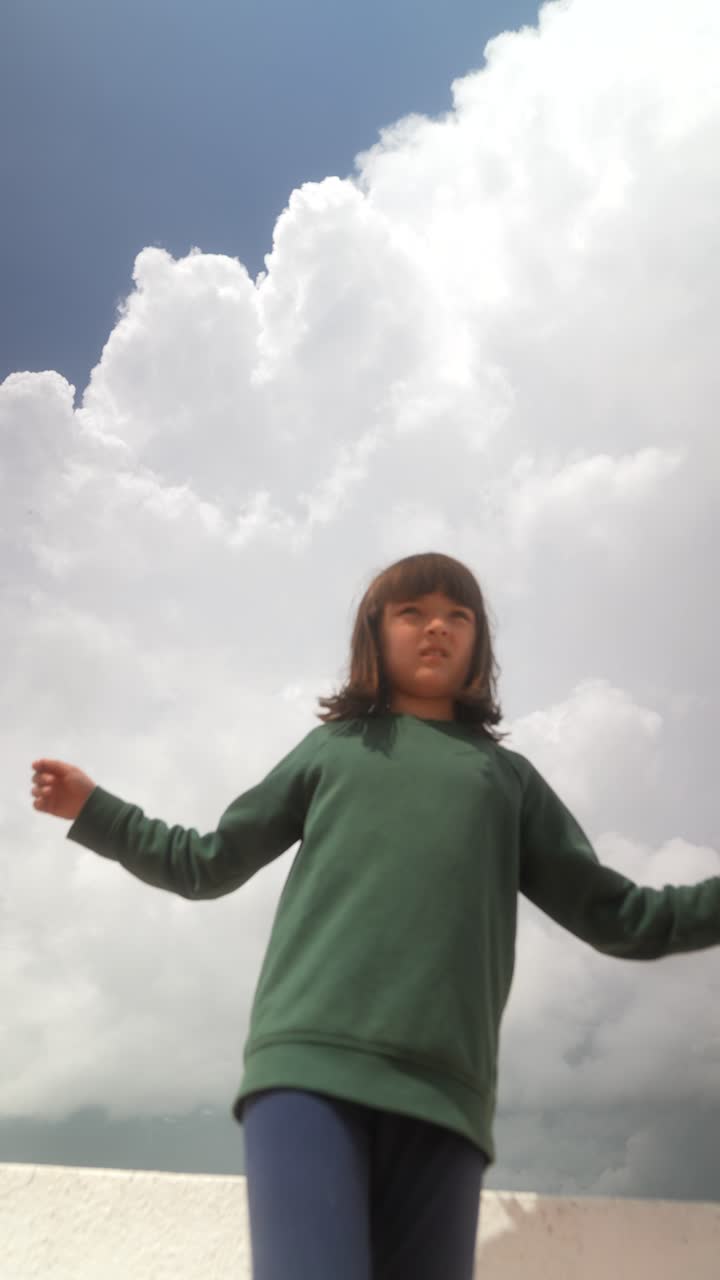 Girl on a wall under a cloudy sky