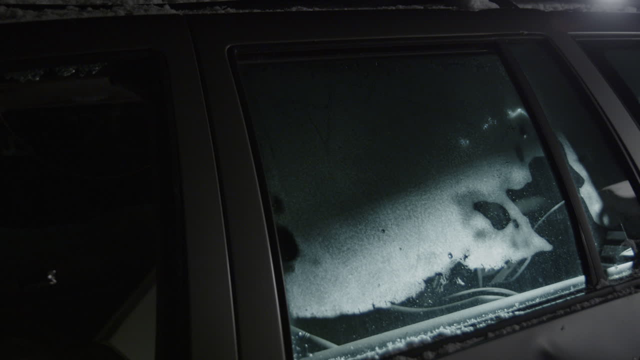 Smashing car window with sledge hammer, shattering glass of vehicle, slow motion