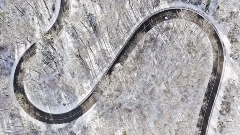 Timelpase-of-a-double-bending,-s-curve-in-a-winter-landscape-with-driving-cars-from-a-top-down-drone-view,-wonderful-framed-snowy-shot