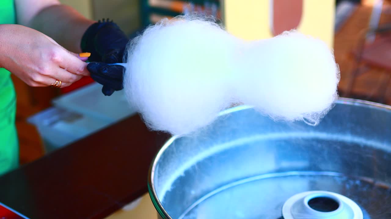 Women is hands are preparing cotton candy in park