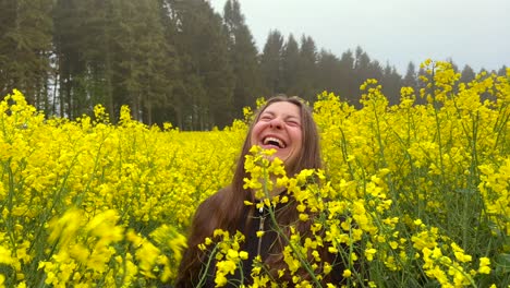 girl laugh inside yellow rapeseed field walks towards camera