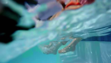 Family-sitting-on-poolside-and-shaking-their-legs-in-pool-water