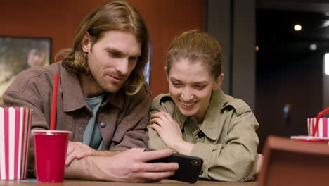 pareja feliz mirando algo divertido en el teléfono móvil en el cine 1