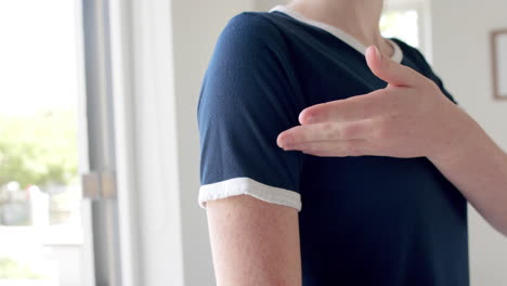 Midsection-of-caucasian-woman-in-navy-blue-t-shirt-showing-white-edging-in-sunny-room,-slow-motion