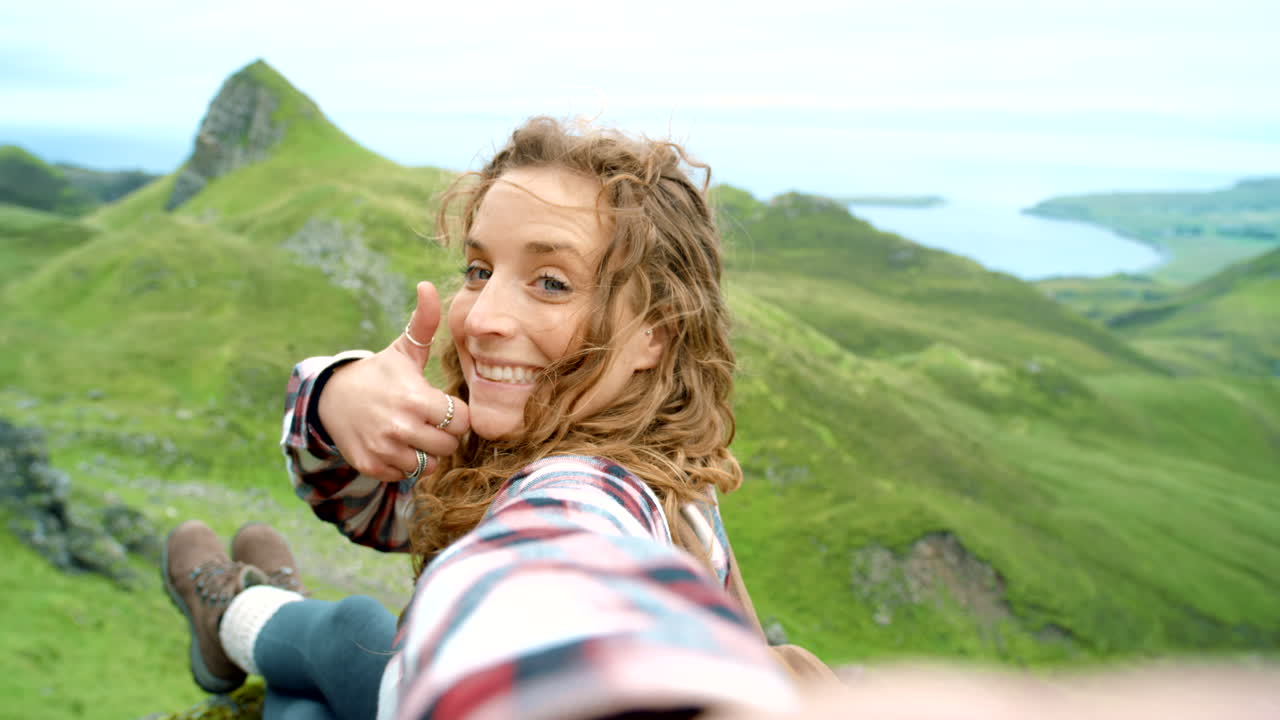 una mujer tomando una selfie en las montañas escocesas.