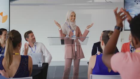 female speaker and applauding audience at a business conference