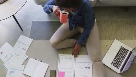 happy african american woman sitting on floor, using laptop and working