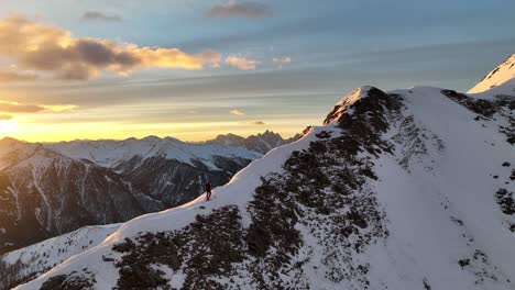 alpine skier during ascent on a ridge after sunrise in the italian alps