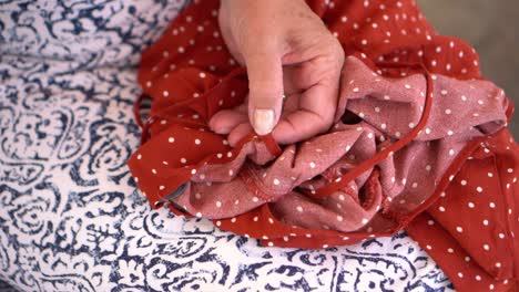 a close up of an old woman's hand fix a dress with a sewing needle