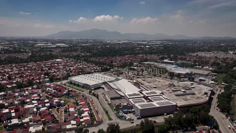 aerial drone shot focusing on a shopping mall in the foreground with the urban sprawl of cuautitlán izcalli municipality, part of the metropolitan area of mexico city, visible on the horizon