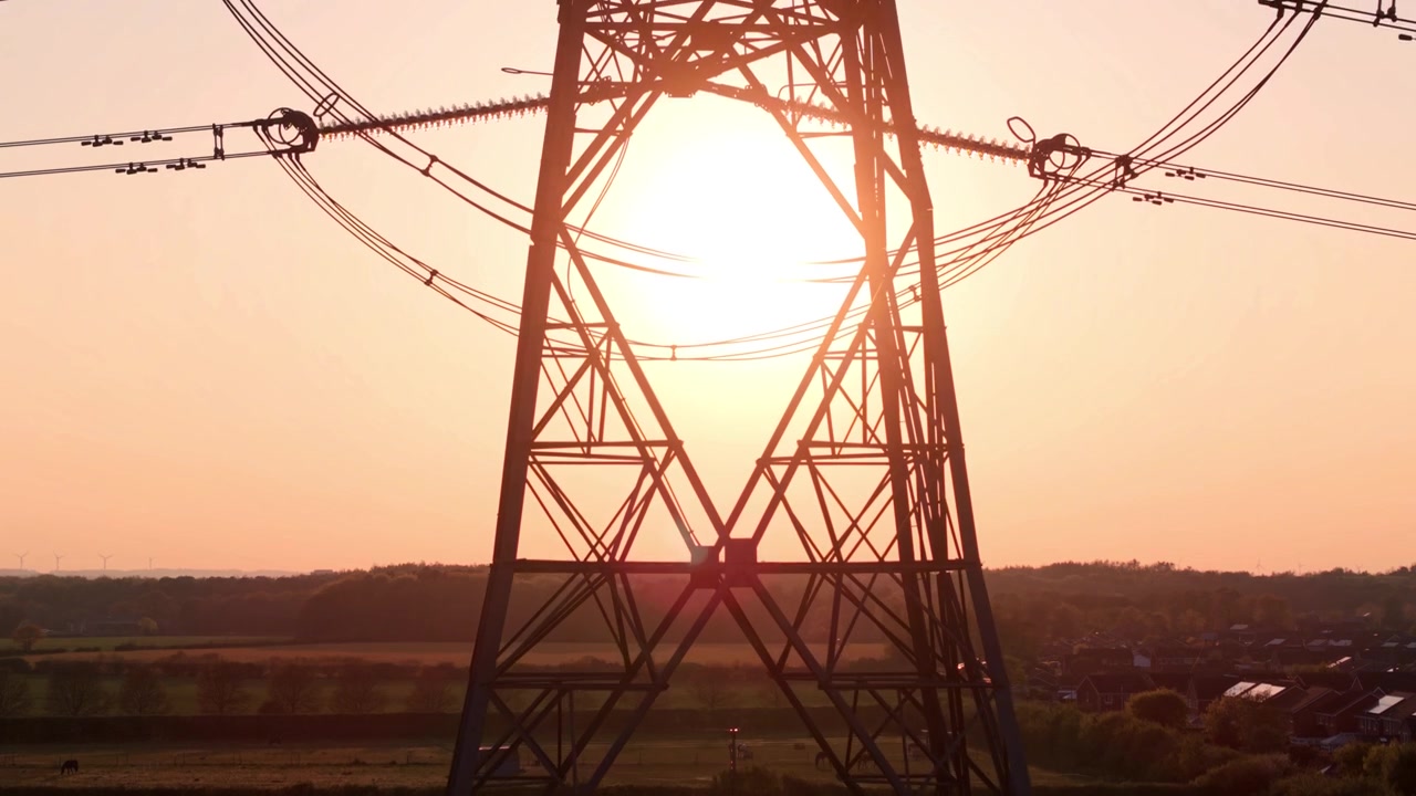 Silhouetted Transmission Tower and Cables at Sunset Drone Flyover in UK