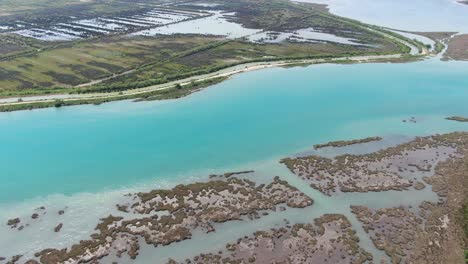 drone view in albania flying over wide blue river and green landscape next to the sea with mountains on the back