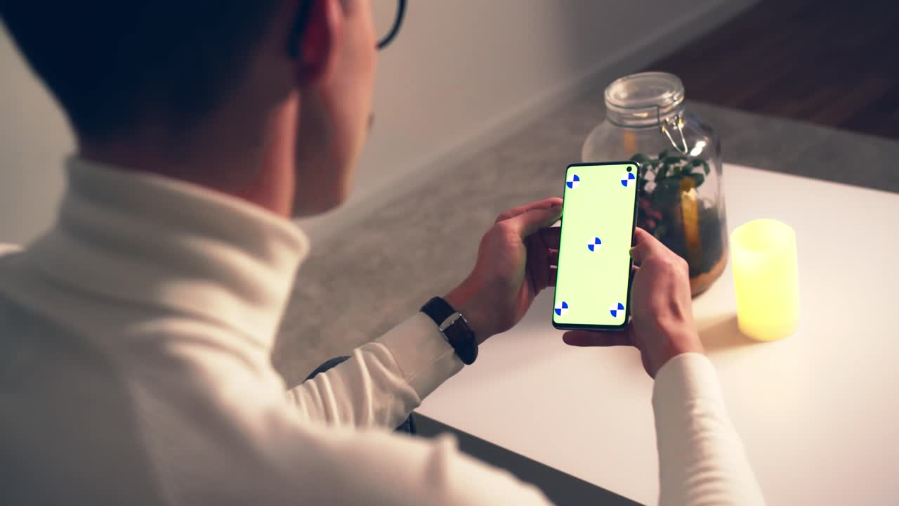 녹색 화면 크로마 키가 있는 스마트폰을 사용하는 편안한 청년