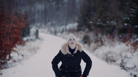 positive woman jumping on snow and playing with scarf in winter 2
