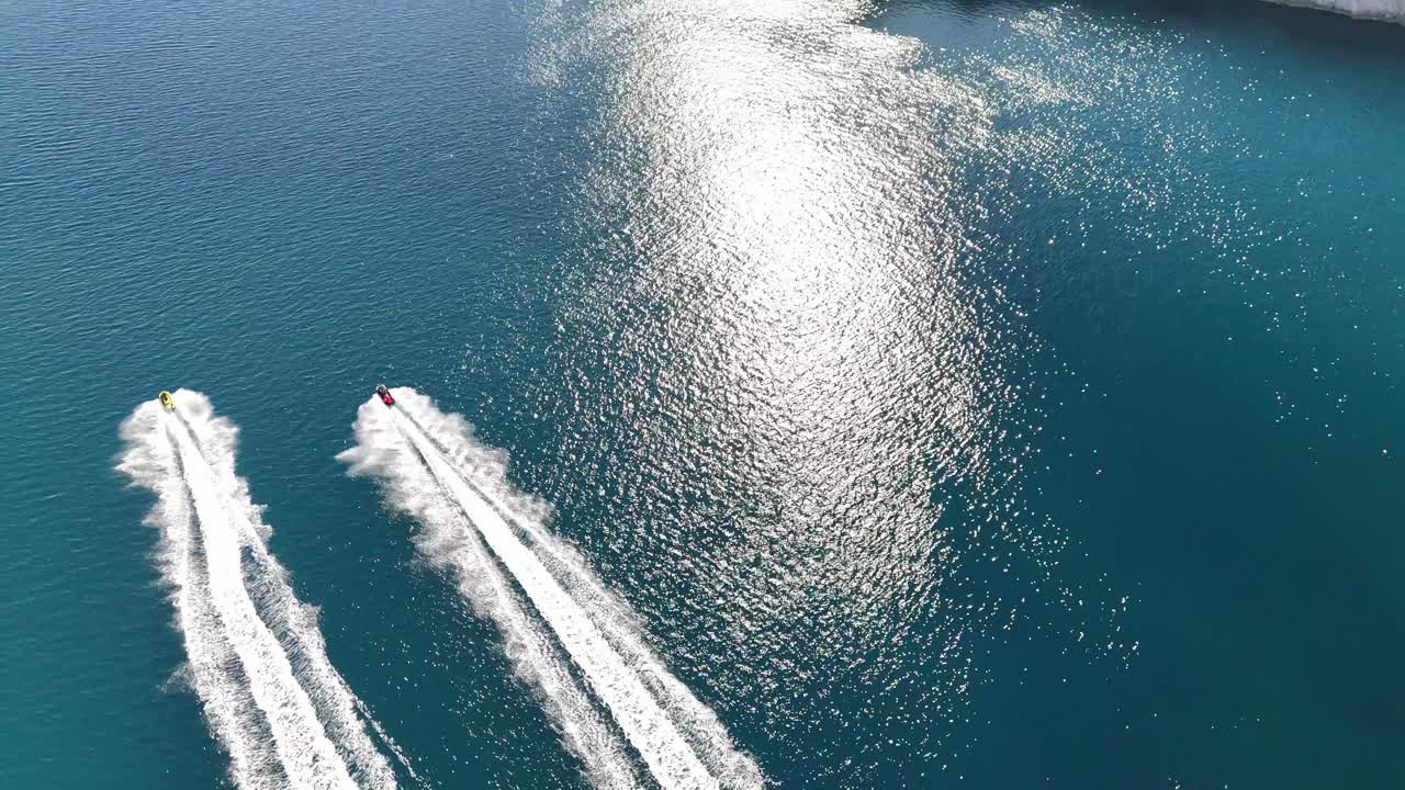 Drone aerial view of Pag Island Bridge, Croatia. Jet skis moving below over the blue Adriatic Sea, camera follows and lifts toward Fortica Fortress and the tip of Pag Island