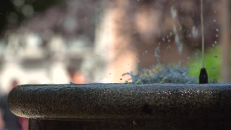 Vista-De-Cerca-De-La-Fuente-De-Agua-Escupiendo-Agua-Con-Un-Fondo-Borroso-En-El-Parque