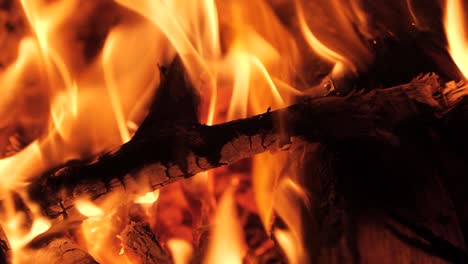 captivating super slow-motion: a mesmerizing close-up as wood embraces the fiery embrace, slowly dissolving in the warm embers of a cozy fireplac