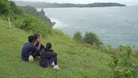 people taking pictures of the ocean view from a hilltop