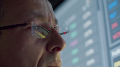 closeup of pensive data engineer with eyeglasses looking at digital monitor