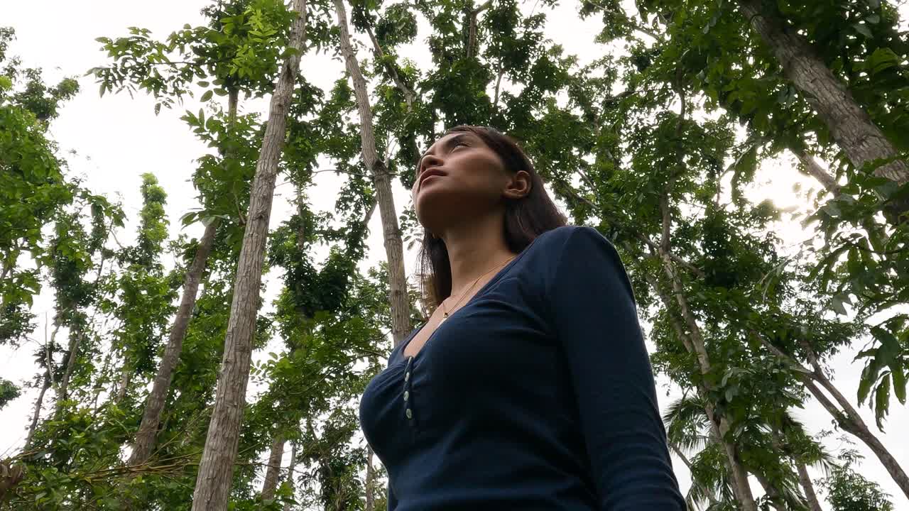 Ritratto di una donna asiatica che si guarda intorno tra gli alberi in una foresta tropicale