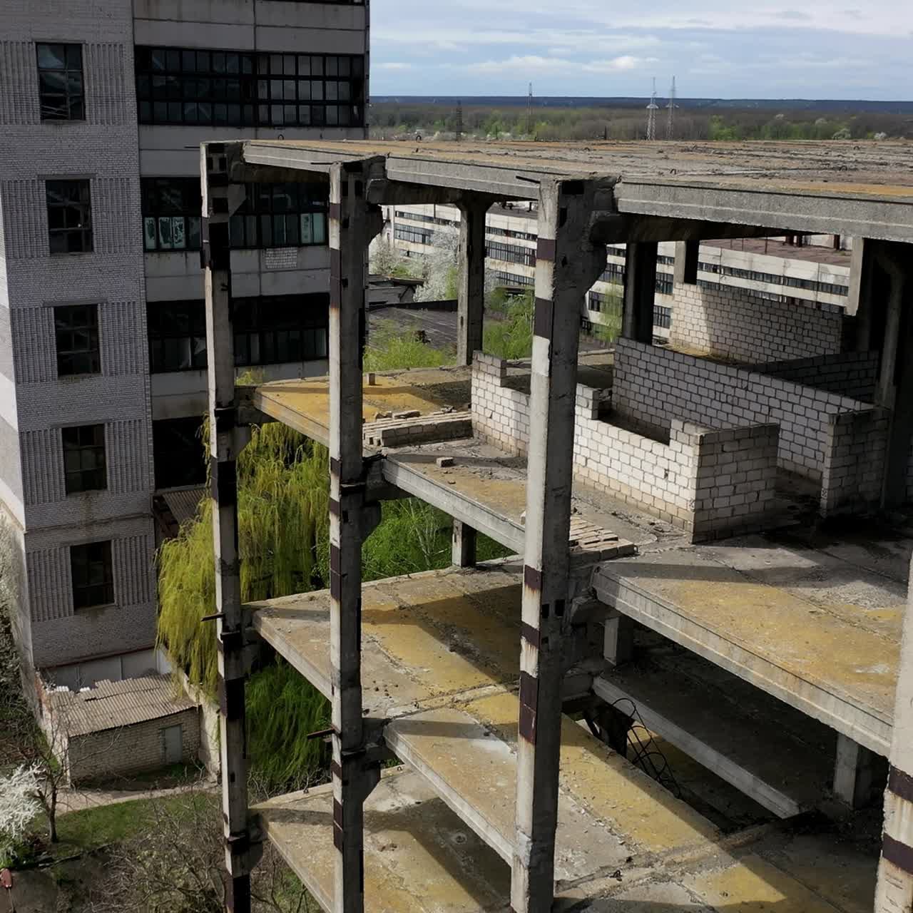 Unfinished building of abandoned factory. Old industrial architecture in spring. Camera rising. Aerial view