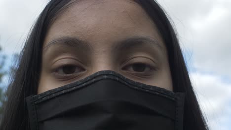 Female-Teenager-Wearing-Face-Mask-Against-Blue-Sky-And-Clouds