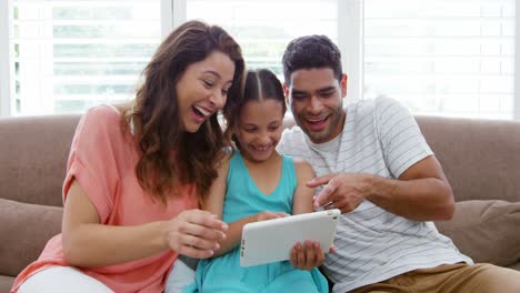 Familia-Feliz-Sentada-En-El-Sofá-Y-Usando-Una-Tableta-Digital